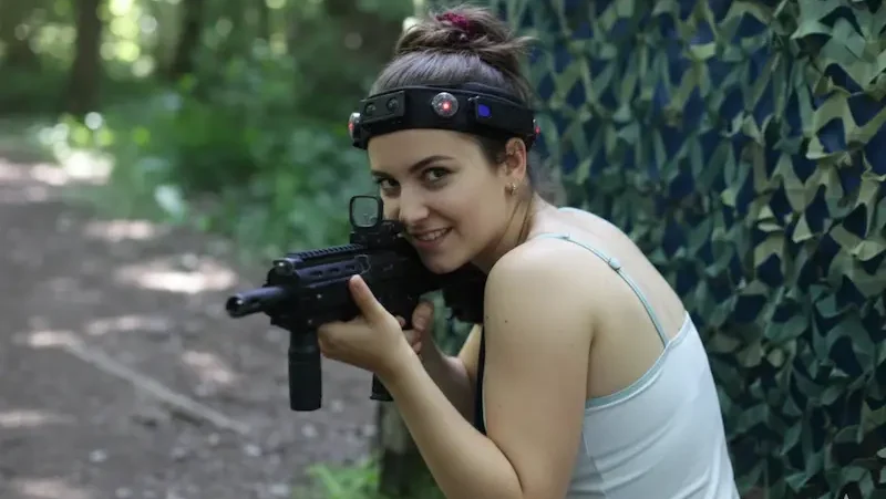 Volle Geschwindigkeit: Das Spiel ist eröffnet. Action Lasertag Wels: Spielerin in schneller Bewegung am Außen-Gelände. Taktisches Manöver im Dschungel.